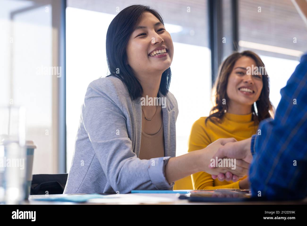 Femme d'affaires asiatique souriante serrant la main pendant la réunion dans un cadre de bureau moderne Banque D'Images