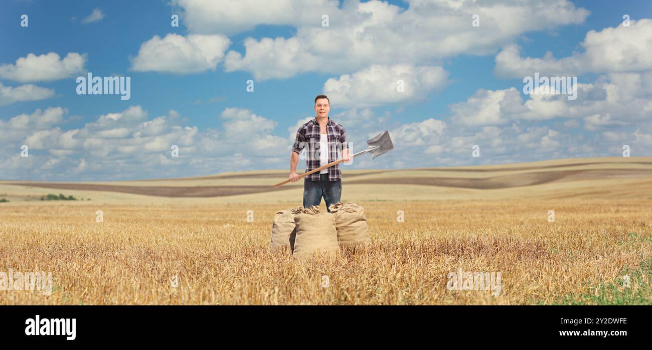 Homme tenant une pelle sur un champ de blé Banque D'Images