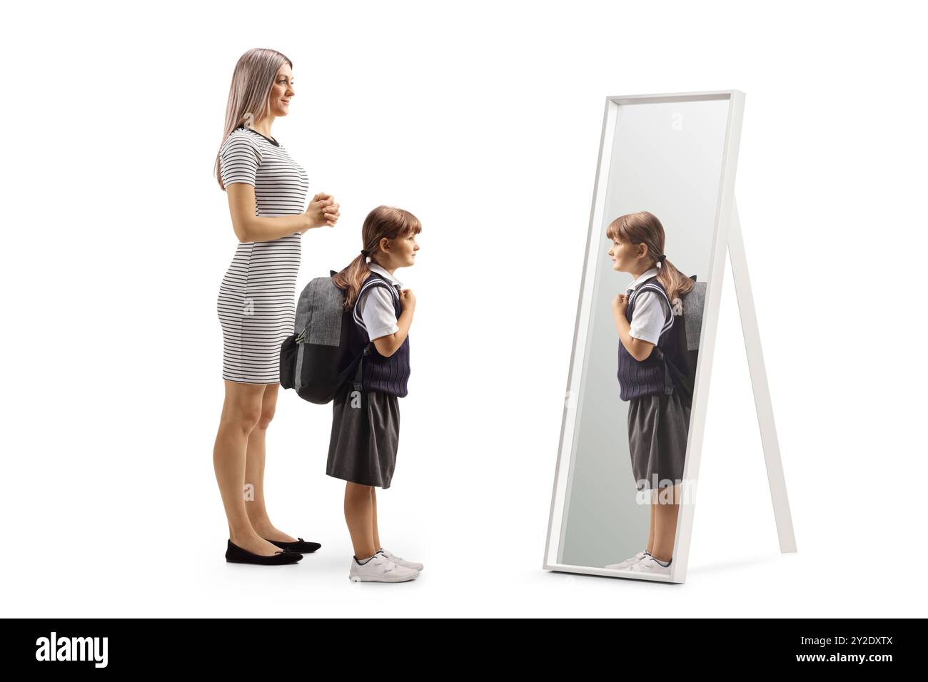 Mère et fille dans un uniforme scolaire se préparant devant un miroir isolé sur fond blanc Banque D'Images