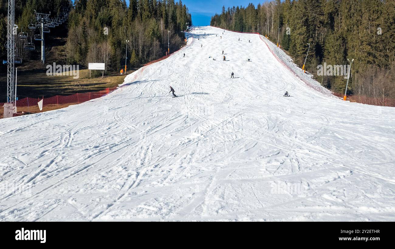 Pente de ski raide, télésiège, skieurs et snowboarders dans la station de ski de Bialka Tatrzanska en Pologne en hiver. Large espace de copie sur la neige ci-dessous Banque D'Images