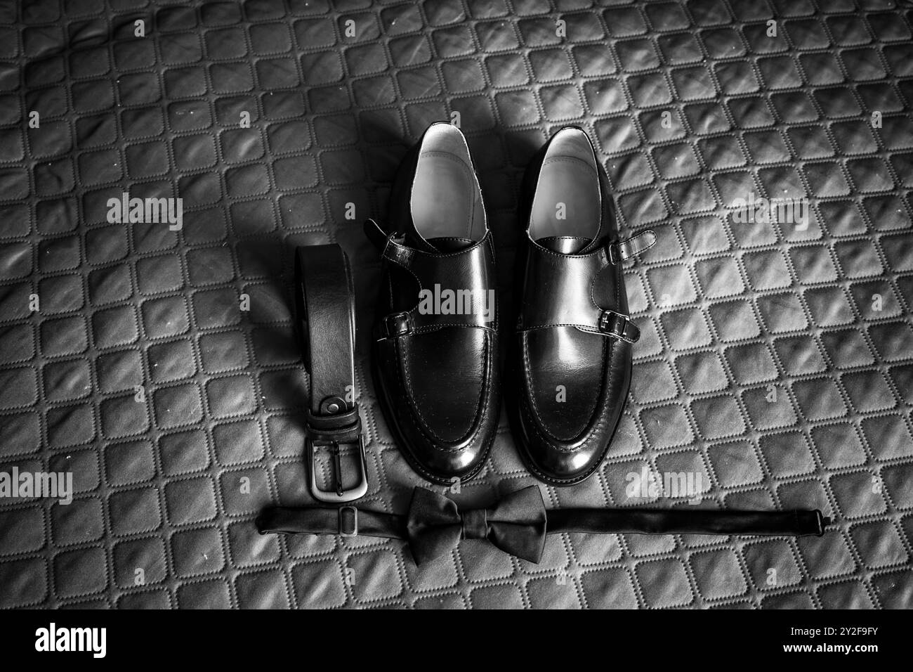 Élégant arrangement noir et blanc d'accessoires formels pour hommes sur surface matelassée. Banque D'Images