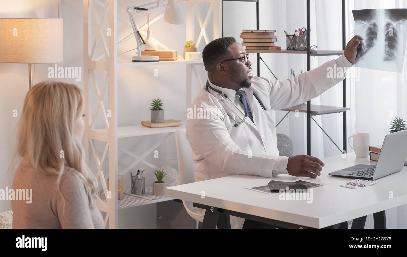 Consultation pathologique. Rendez-vous chez le médecin. Diagnostic des pneumonies. Médecin généraliste sérieux expliquant la radiographie pulmonaire à une patiente hospitalière. Banque D'Images