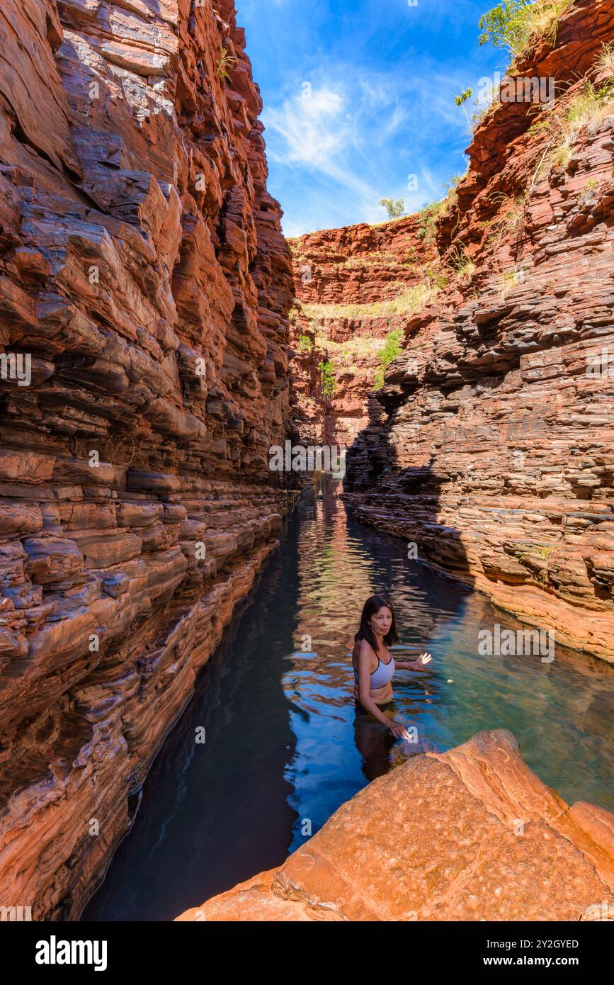 Une aventurière femme traverse l'étroite gorge de Hancock, aux parois escarpées et remplies d'eau, dans le magnifique parc national de Karijini en Australie. Banque D'Images