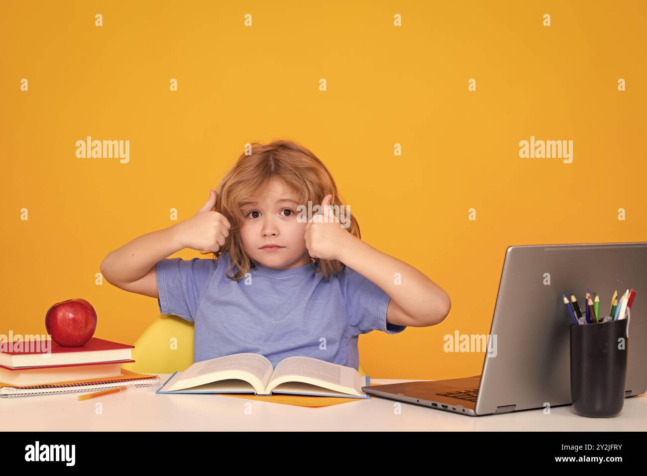 Petit enfant étudiant isolé sur fond de studio. Portrait de l'élève nerd avec fournitures scolaires Banque D'Images