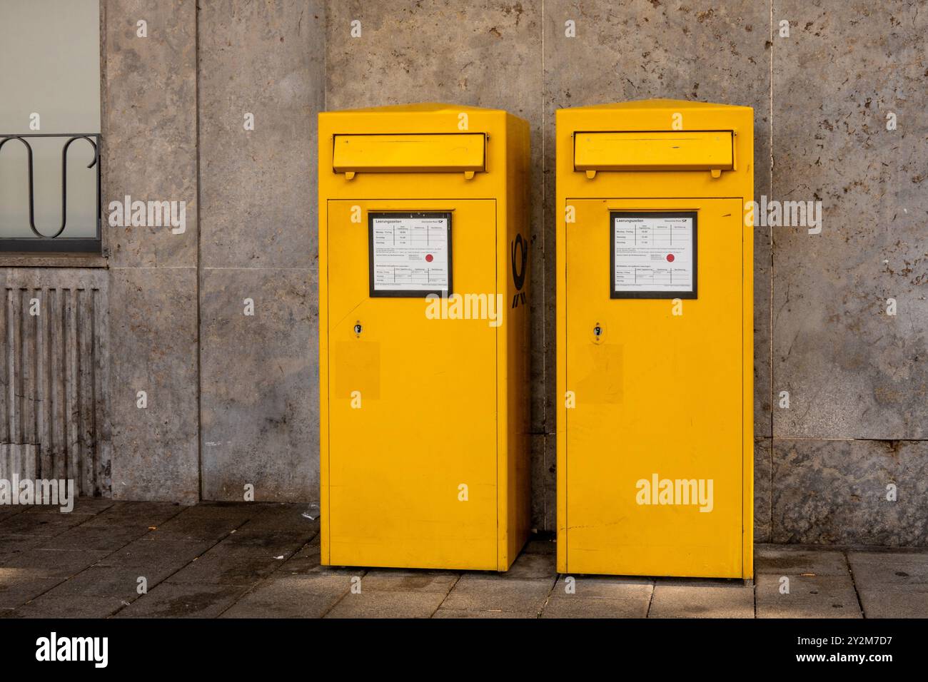 Trèves, Allemagne - 7 septembre 2024 : deux boîtes aux lettres jaune vif se tiennent côte à côte contre un mur de pierre grise. Ils sont conçus pour envoyer des lettres A. Banque D'Images