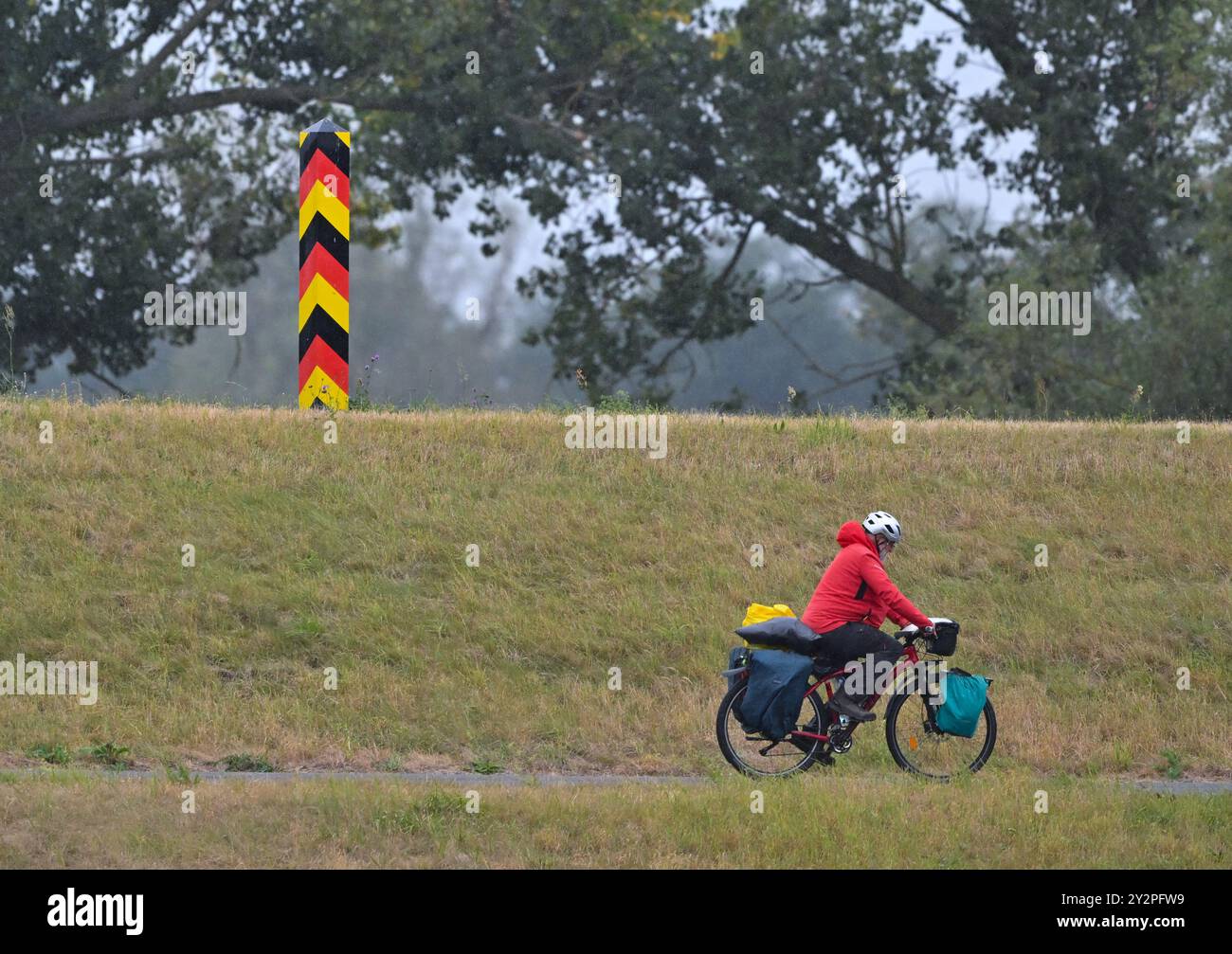 Reitwein, Allemagne. 11 septembre 2024. Un cycliste roule sous la pluie sur la piste cyclable Oder-Neisse dans l'Oderbruch à l'est du Brandebourg. Le temps d'automne continue à Berlin et Brandebourg. Des orages locaux sont attendus - et les températures chutent, selon le Service météorologique allemand (DWD). Crédit : Patrick Pleul/dpa/Alamy Live News Banque D'Images