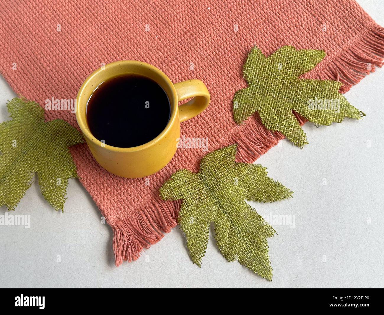 Automne, tasse à café jaune et textile orange, et feuilles d'automne vertes Banque D'Images