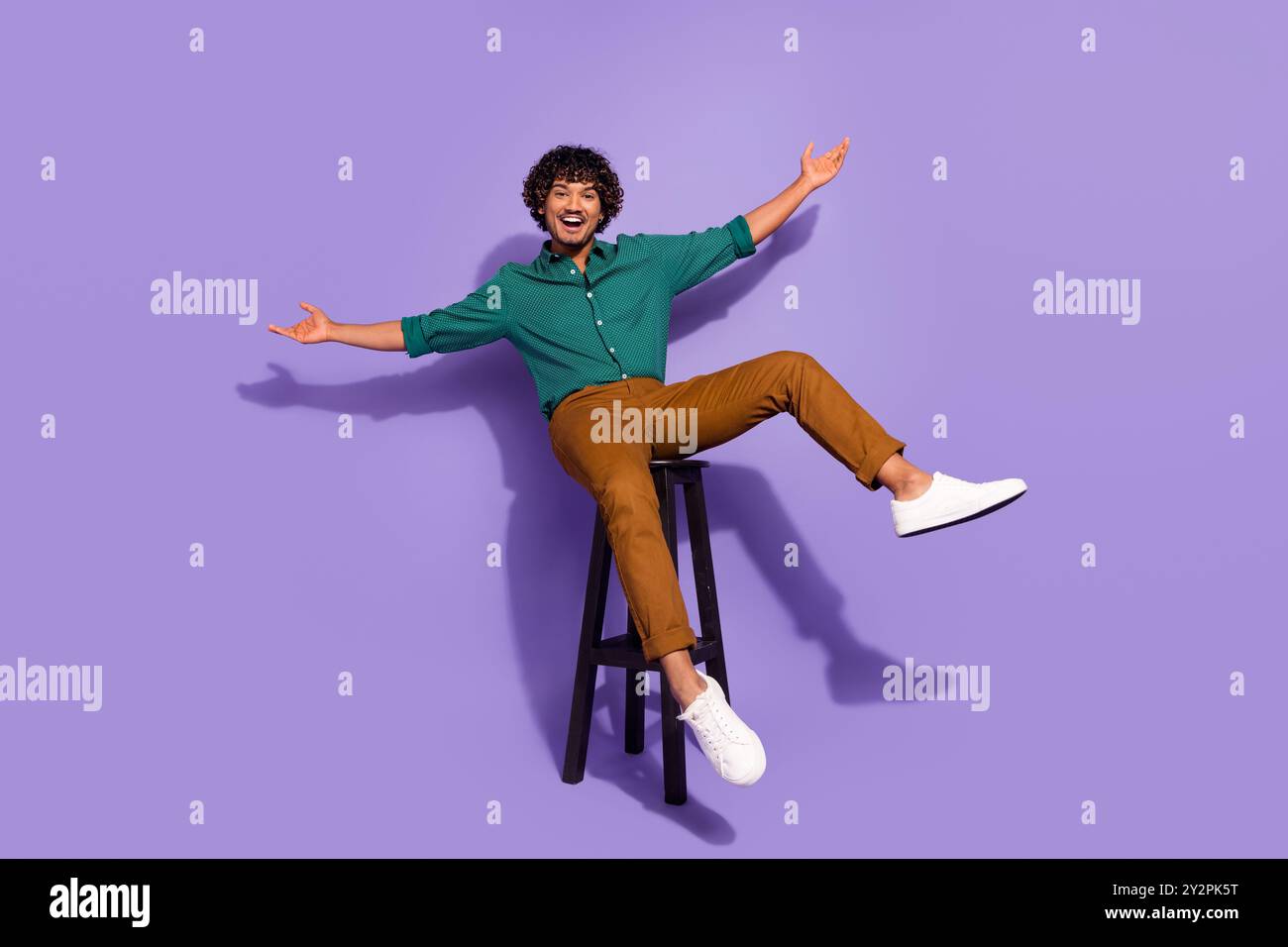 Photo pleine longueur du corps du beau gars hispanique dans le bar se rafraîchissant assis chaise de barman sans soucis détente isolé sur fond de couleur violette Banque D'Images