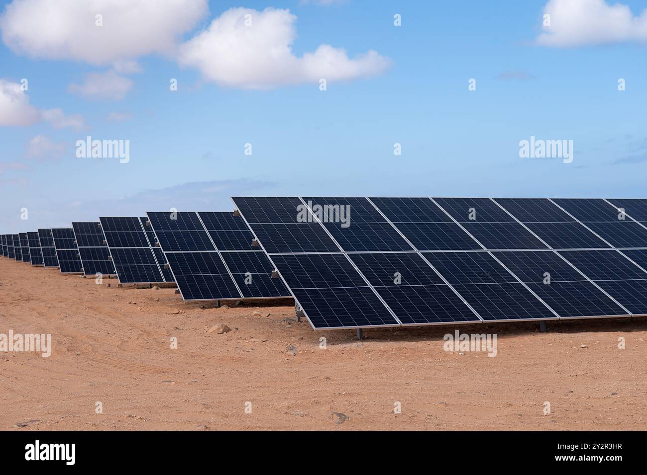 Un paysage présentant des rangées de panneaux solaires installés dans un cadre désertique, reflétant la production d’énergie durable sous un ciel bleu clair Banque D'Images