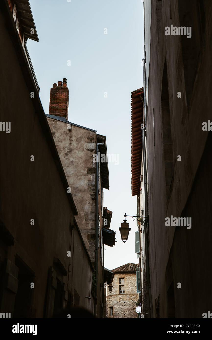 Vue sereine sur une ruelle étroite à Bayonne, avec des bâtiments rustiques, un lampadaire vintage et des volets traditionnels. Banque D'Images