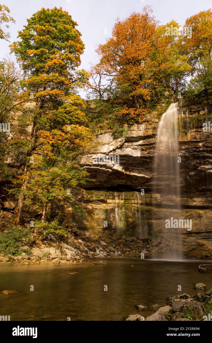 Vue panoramique sur la cascade Cascade le saut Girard entourée d'un feuillage d'automne dynamique dans la région du Jura français, mettant en valeur la beauté tranquille de la nature. Banque D'Images