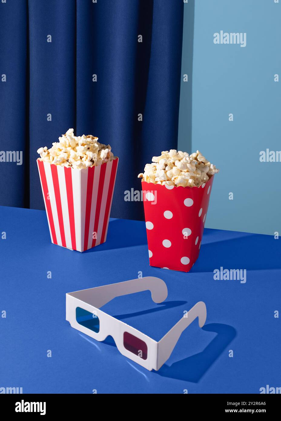 Image vibrante avec deux seaux à pop-corn et une paire de lunettes 3D sur un fond bleu profond, capturant l'essence de la soirée cinéma. Banque D'Images