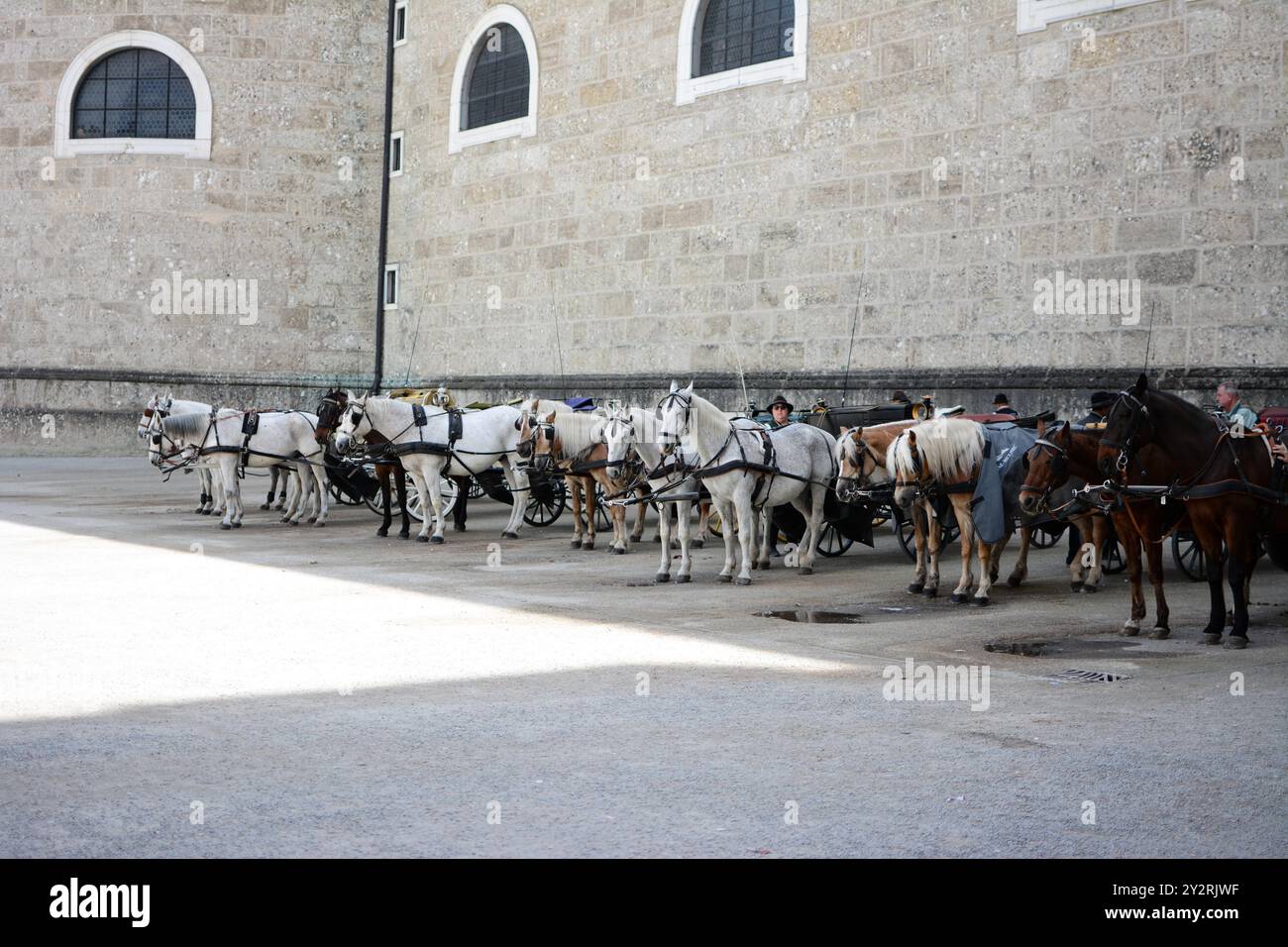 Une file de calèches avec des chauffeurs attendant près d'un bâtiment historique en pierre dans une ville européenne Banque D'Images