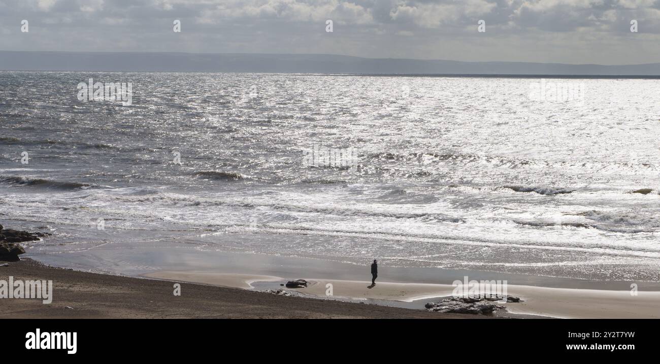 11 septembre 2024, Hardy’s Bay, Ogmore-by-Sea, Bridgend, Vale of Glamorgan, pays de Galles. MÉTÉO : vents forts et courants forts à marée décroissante, au milieu du soleil et des nuages à Ogmore by Sea aujourd'hui. La pluie est prévue pour plus tard dans l'après-midi. SUR LA PHOTO : lumière du soleil reflétée dans la mer. MARÉE HAUTE : 11.31. Marée BASSE ; 17 :48 PHOTO : un homme célibataire silhouette sur le rivage, regardant au-dessus du canal de Bristol. Bridget Catterall/Alamy Live News Banque D'Images