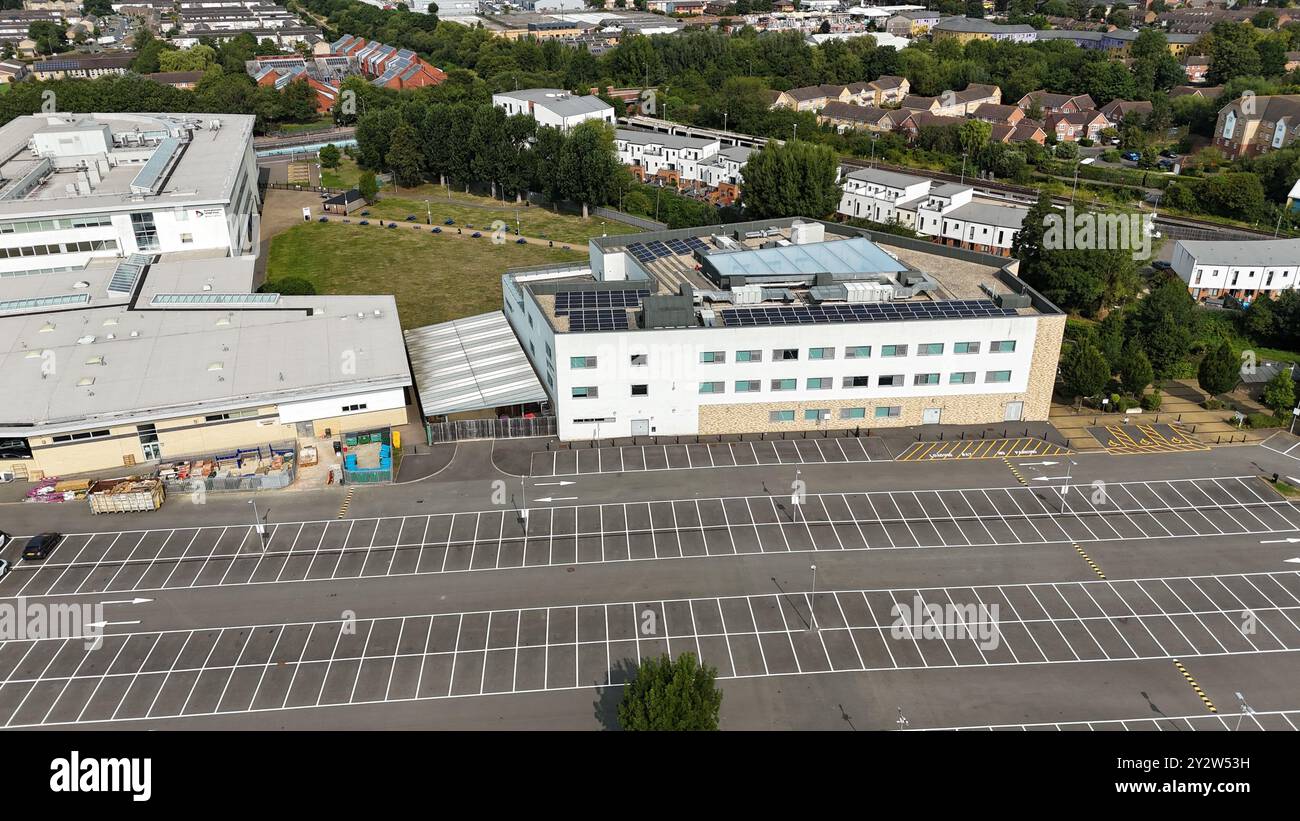 Vue aérienne d'un bâtiment moderne avec panneaux solaires et un parking vide adjacent dans une banlieue. Banque D'Images