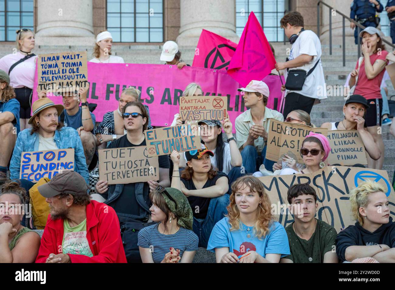 Manifestants avec des pancartes et des drapeaux assis sur les escaliers du Parlement lors de la manifestation d'Elokapina sur le changement climatique Myrskyvaroitus à Helsinki, Finlande Banque D'Images