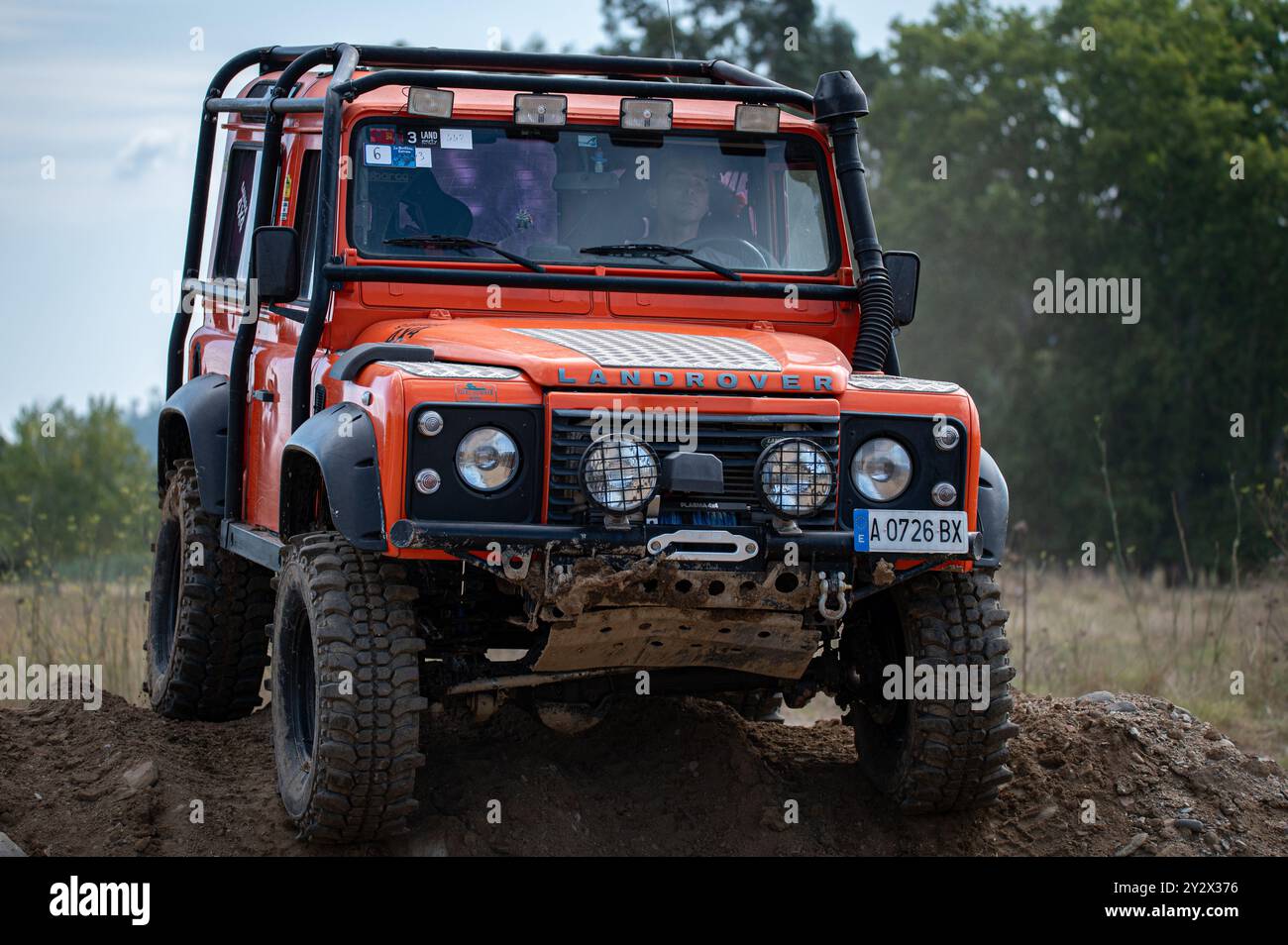 Vue avant rapprochée d'un joli Land Rover Defender orange hautement modifié pour les déplacements hors route extrêmes dans la campagne boueuse Banque D'Images
