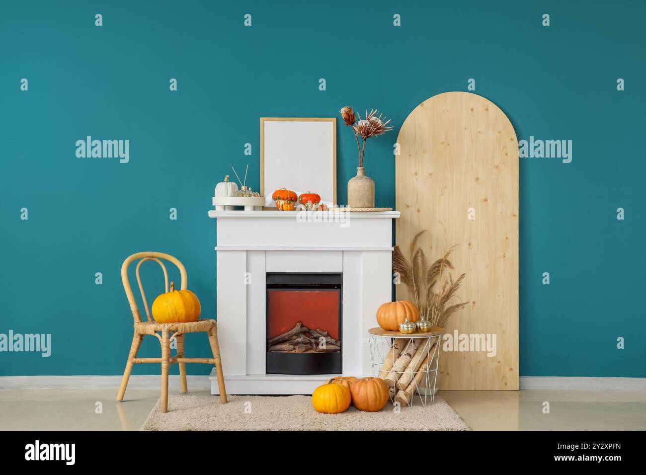 Cheminée blanche, panier avec bûches en bois et citrouilles dans le salon d'automne Banque D'Images