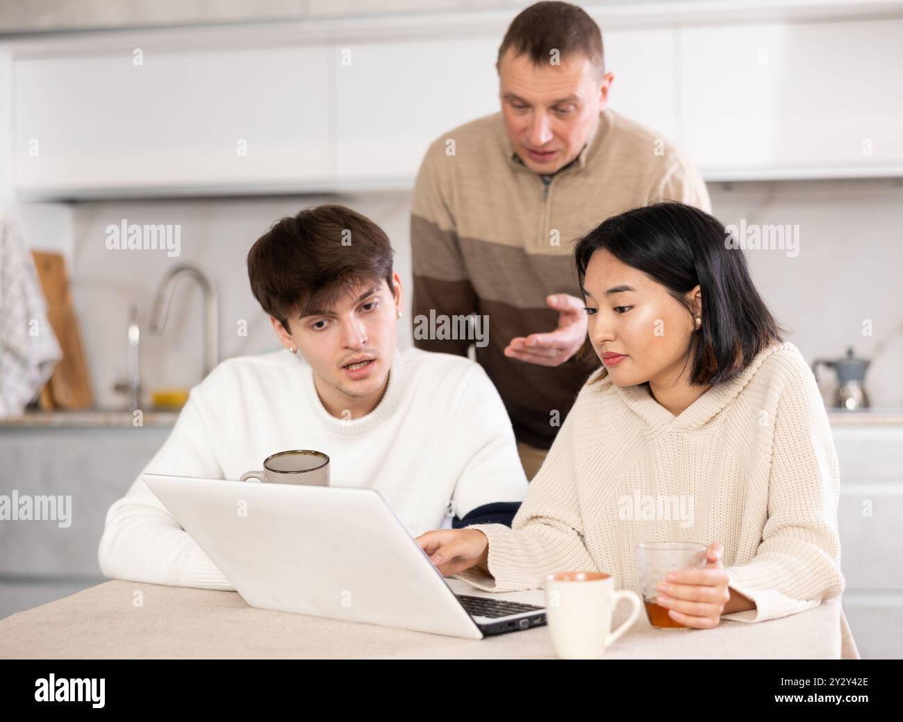 Une famille amicale regarde quelque chose ensemble sur Internet ou des chats vidéo via un ordinateur portable Banque D'Images