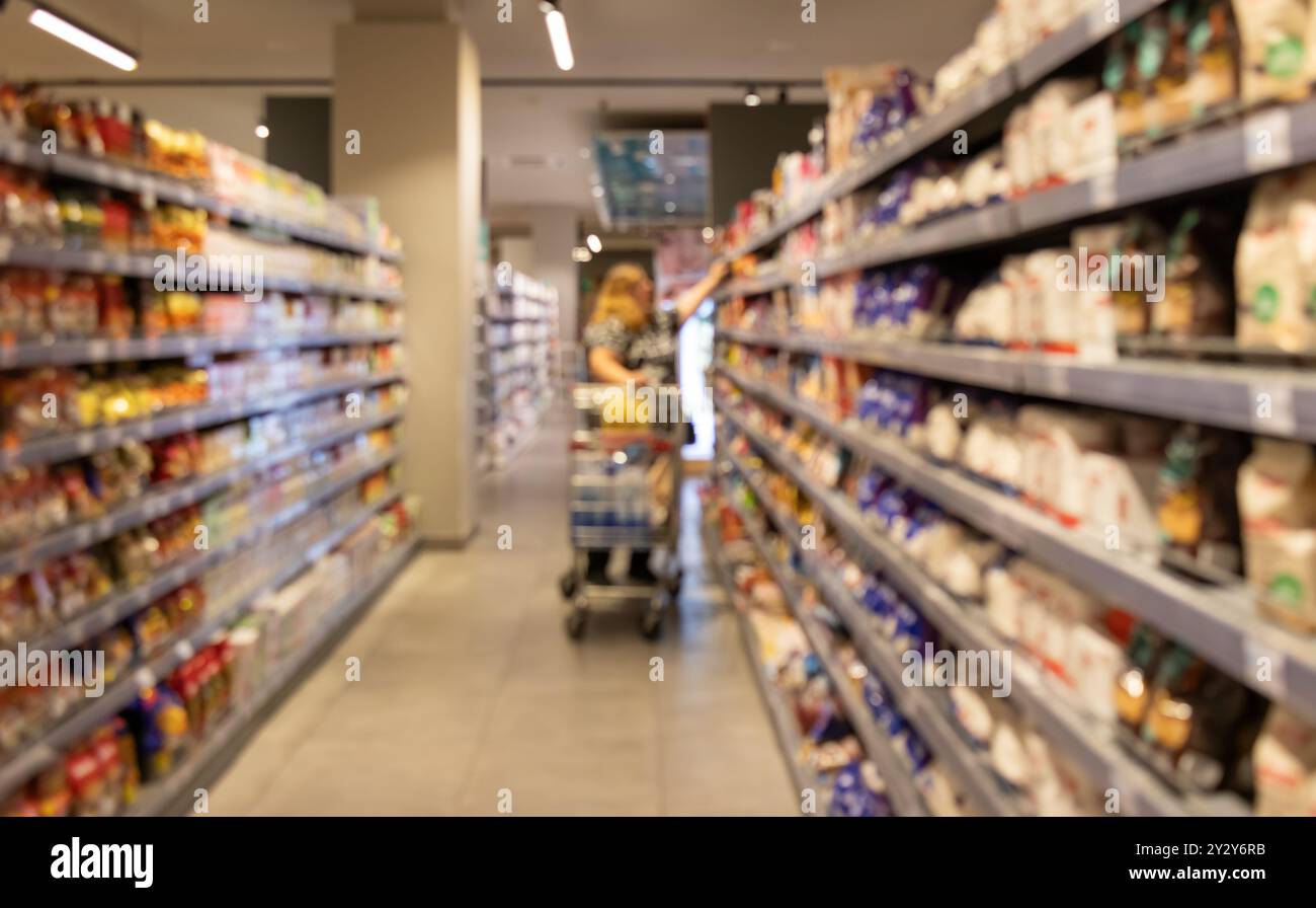 Étagères abstraites floues dans un supermarché. Décor flou à l'intérieur de l'épicerie, large gamme de marchandises, allée de supermarché dynamique, environnement de magasinage Banque D'Images