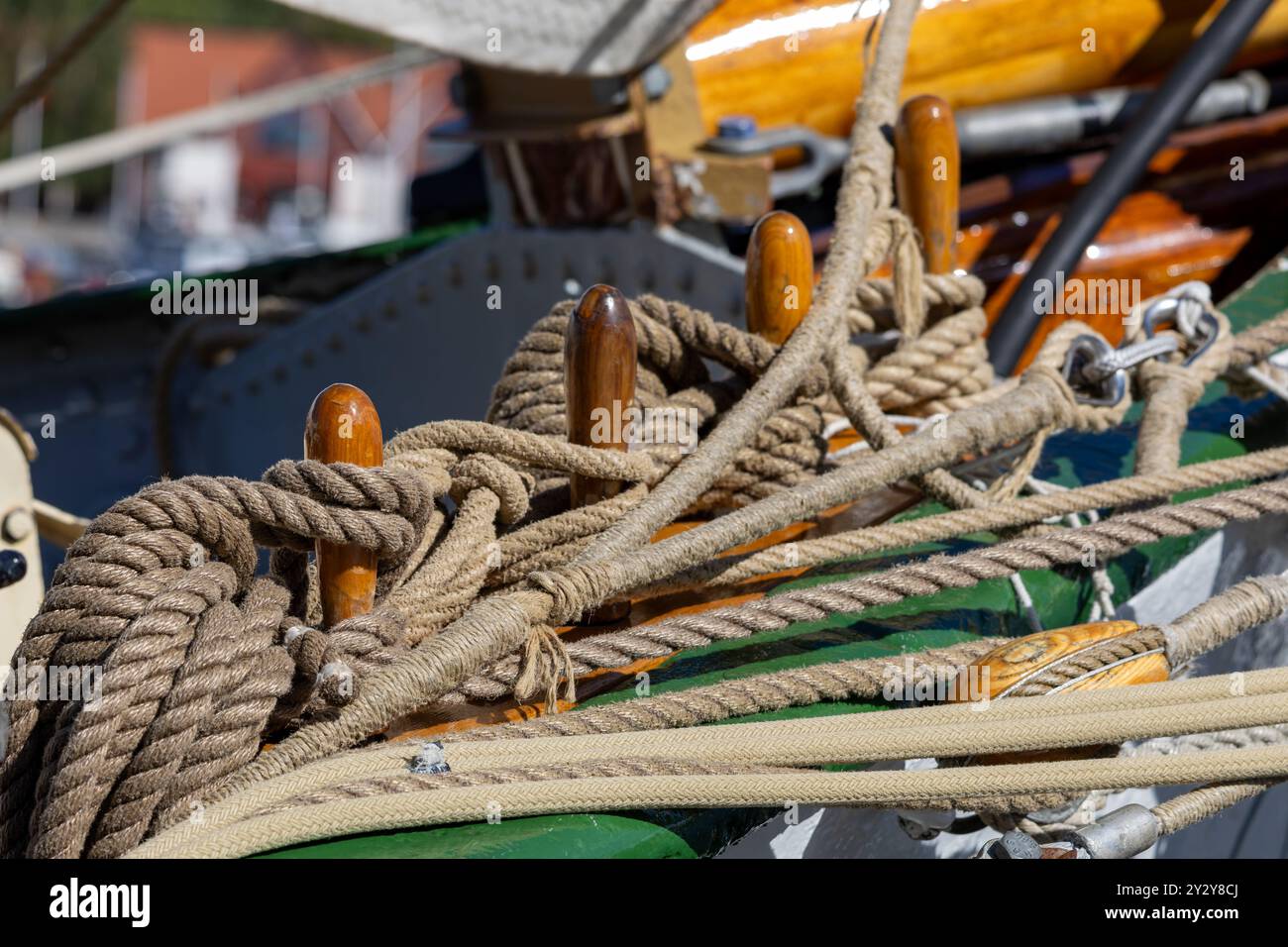 Gros plan de cordes nautiques et de crampons en bois sur un pont de bateau, mettant en valeur des nœuds complexes et des détails maritimes. Banque D'Images