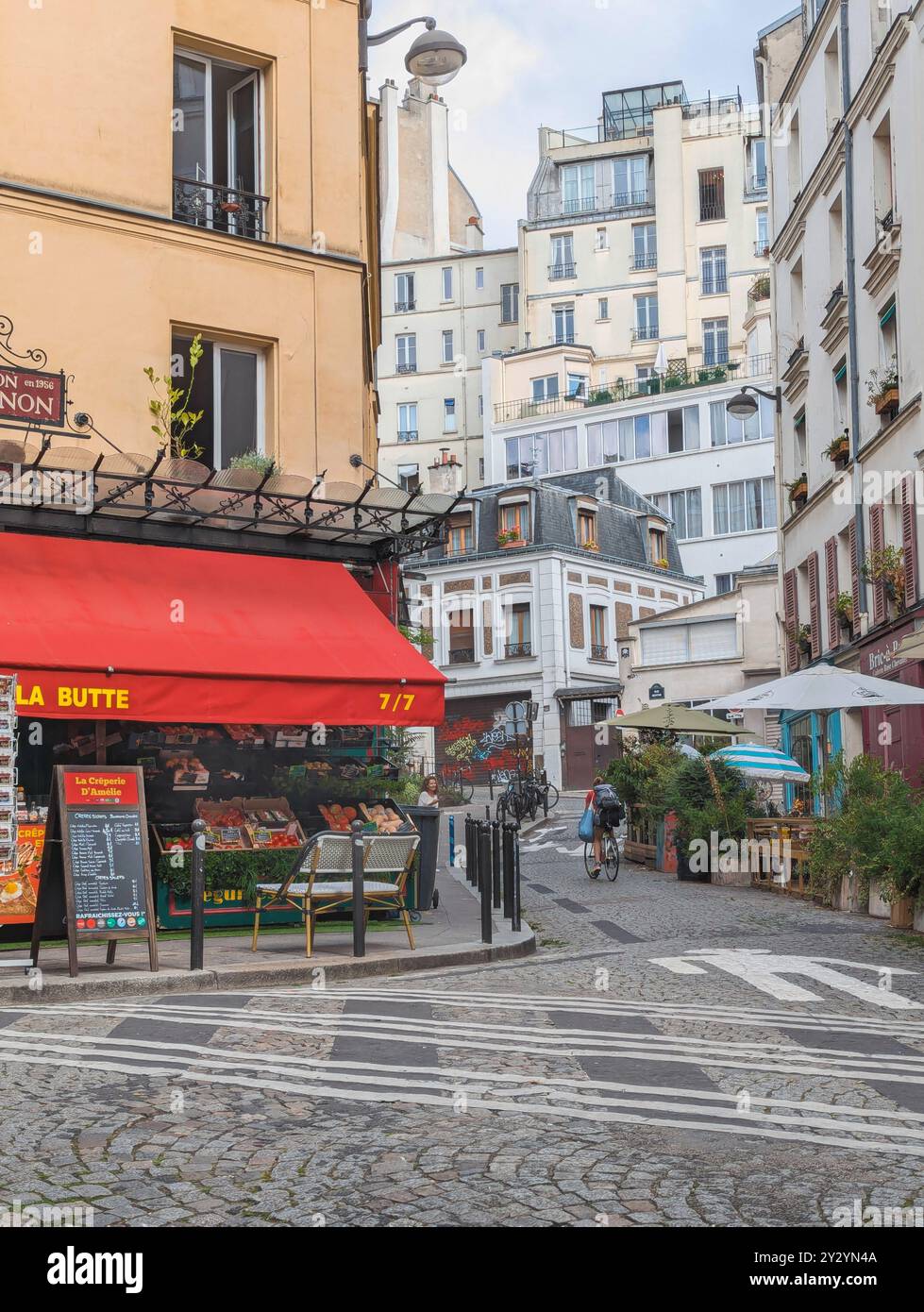 Paris - 04 septembre 2024 - pittoresque rue française de Montmartre avec café et cycliste Banque D'Images