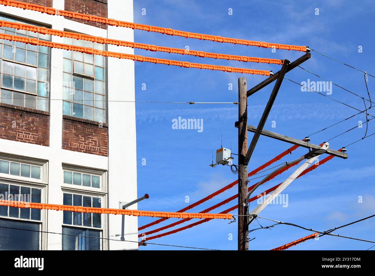 Couvercles de ligne électrique, protections de ligne de sécurité orange couvrant les fils électriques sur un poteau de service à proximité d'un chantier de construction pour la sécurité des travailleurs Banque D'Images