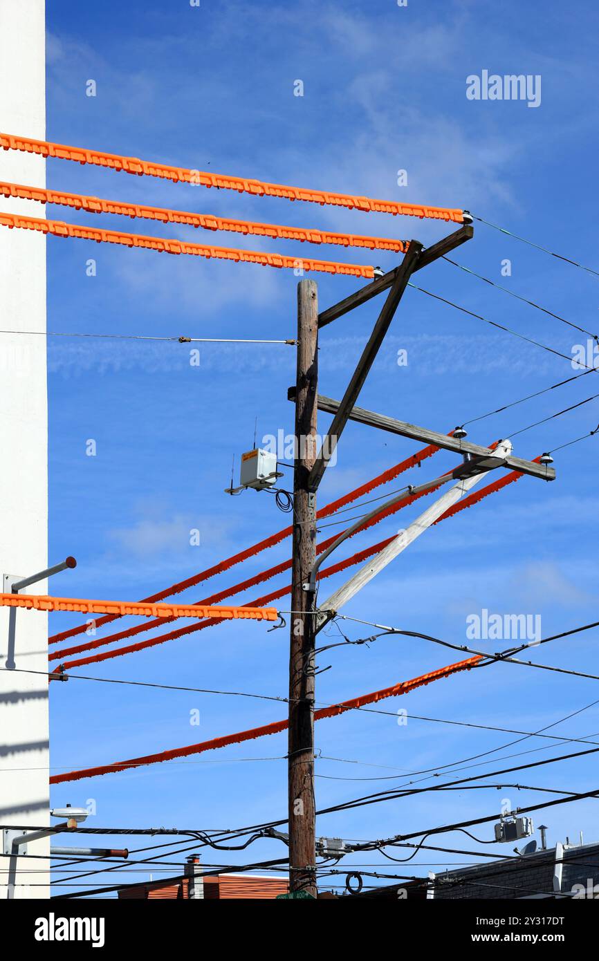 Couvercles de ligne électrique, protections de ligne de sécurité orange couvrant les fils électriques sur un poteau de service à proximité d'un chantier de construction pour la sécurité des travailleurs Banque D'Images