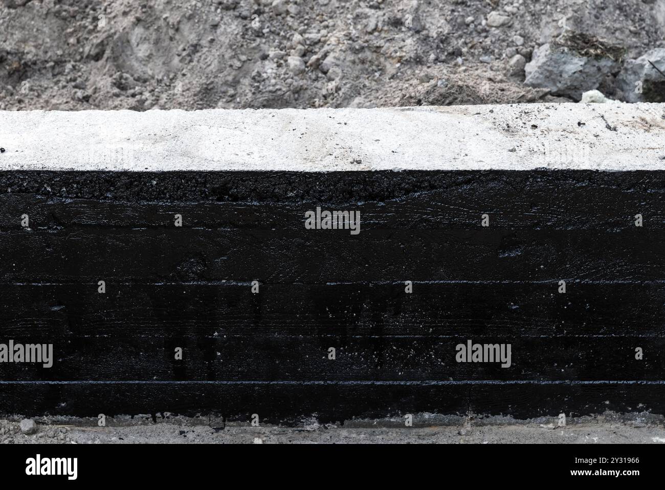 Le mur de fondation en bande en béton armé est recouvert d'une composition de bitume noir de protection, vue de face Banque D'Images