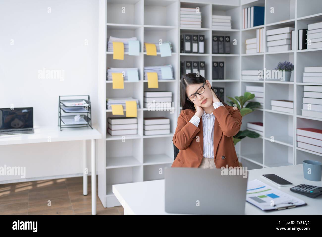 femme d'affaires planifie un audit financier, examinant des documents tout en luttant contre le syndrome de l'épuisement professionnel Banque D'Images