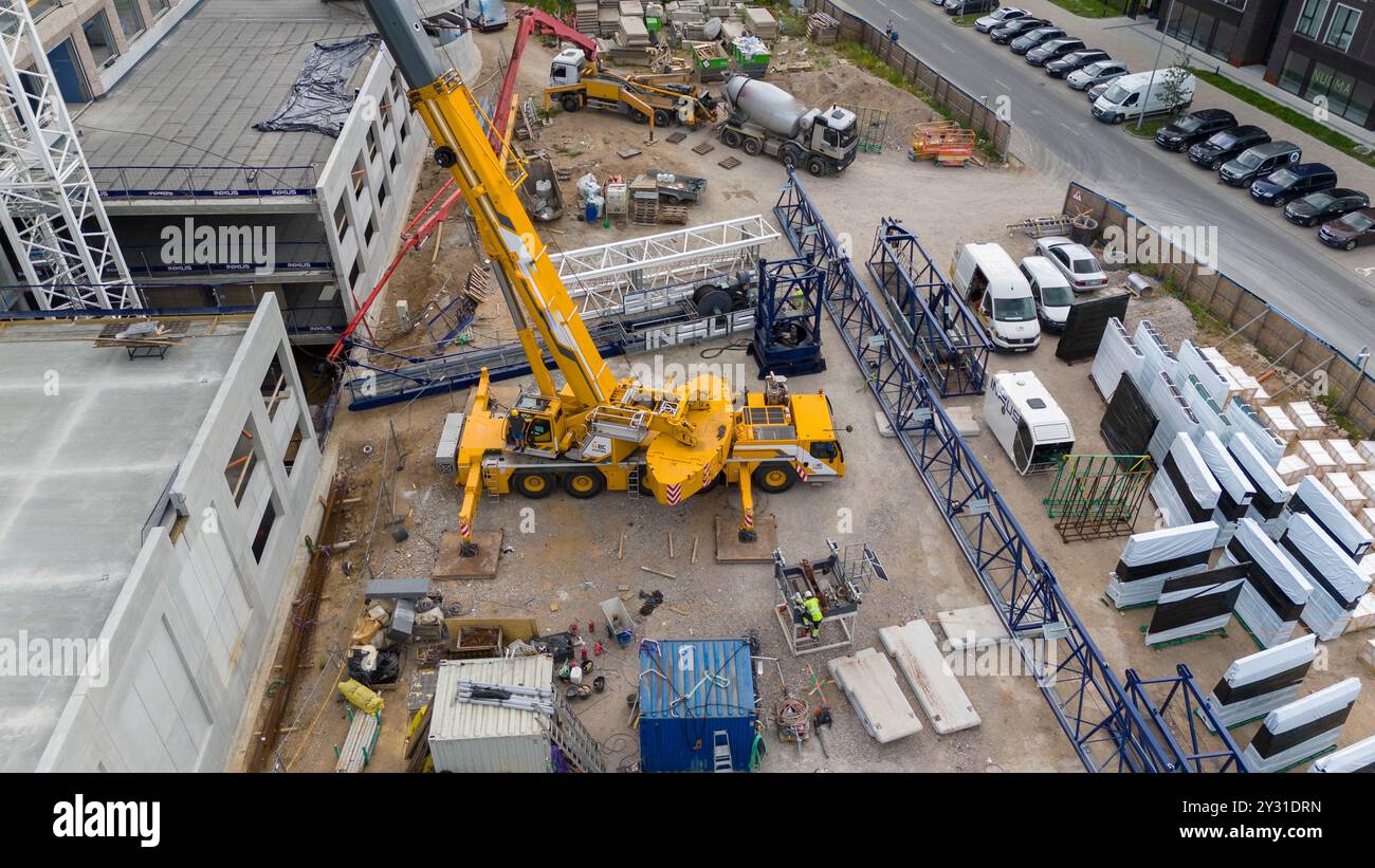 Vue aérienne d'un chantier de construction présentant des grues, des véhicules de construction et des matériaux de construction. Ouvriers de la construction enlevant la grande grue avec sma Banque D'Images