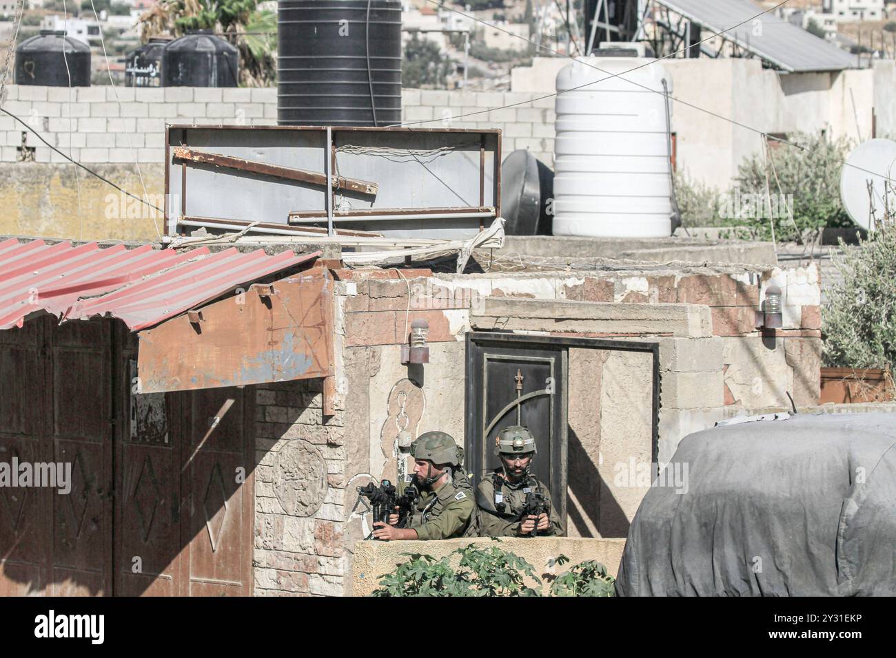 Tubas, Palestine. 11 septembre 2024. Deux soldats israéliens visent alors qu'ils montent la garde lors d'un raid sur une maison palestinienne pendant le raid sur la ville de Tubas. Un raid militaire israélien de grande envergure contre la ville de Tubas, dans le nord de la Cisjordanie occupée, a permis de tuer cinq Palestiniens dans une frappe aérienne et les forces ont encerclé un hôpital palestinien et empêché le personnel médical de transporter des patients à destination et en provenance de celui-ci. Crédit : SOPA images Limited/Alamy Live News Banque D'Images