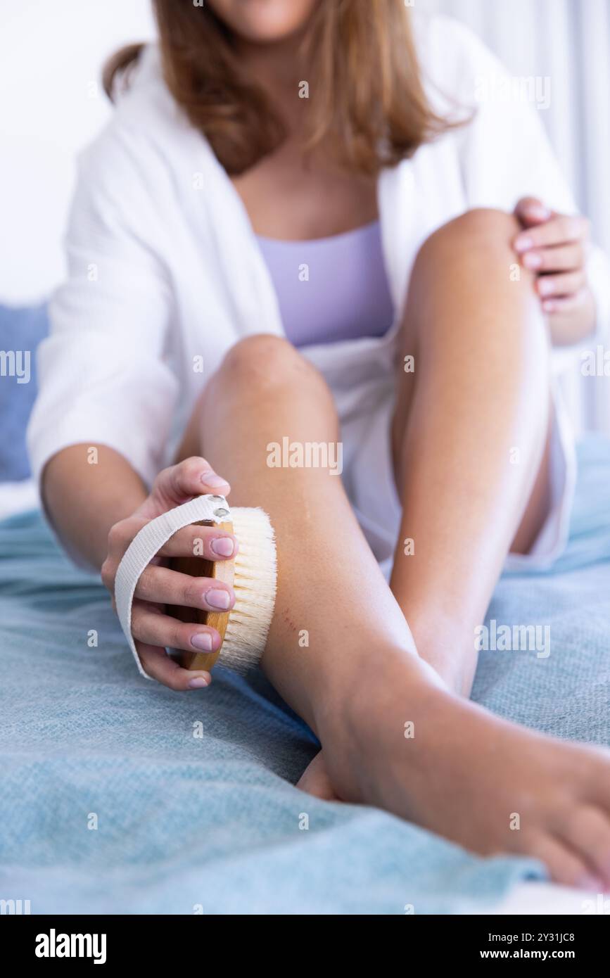 Jambes exfoliantes avec brosse, femme profitant de la routine d'auto-soins au spa à la maison Banque D'Images