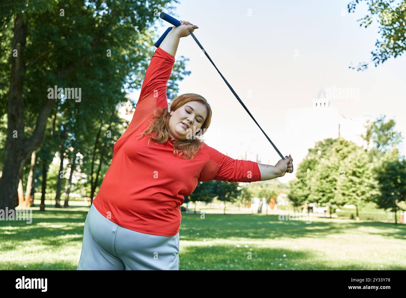 Une femme de grande taille aime s'étirer à l'extérieur dans un parc animé. Banque D'Images