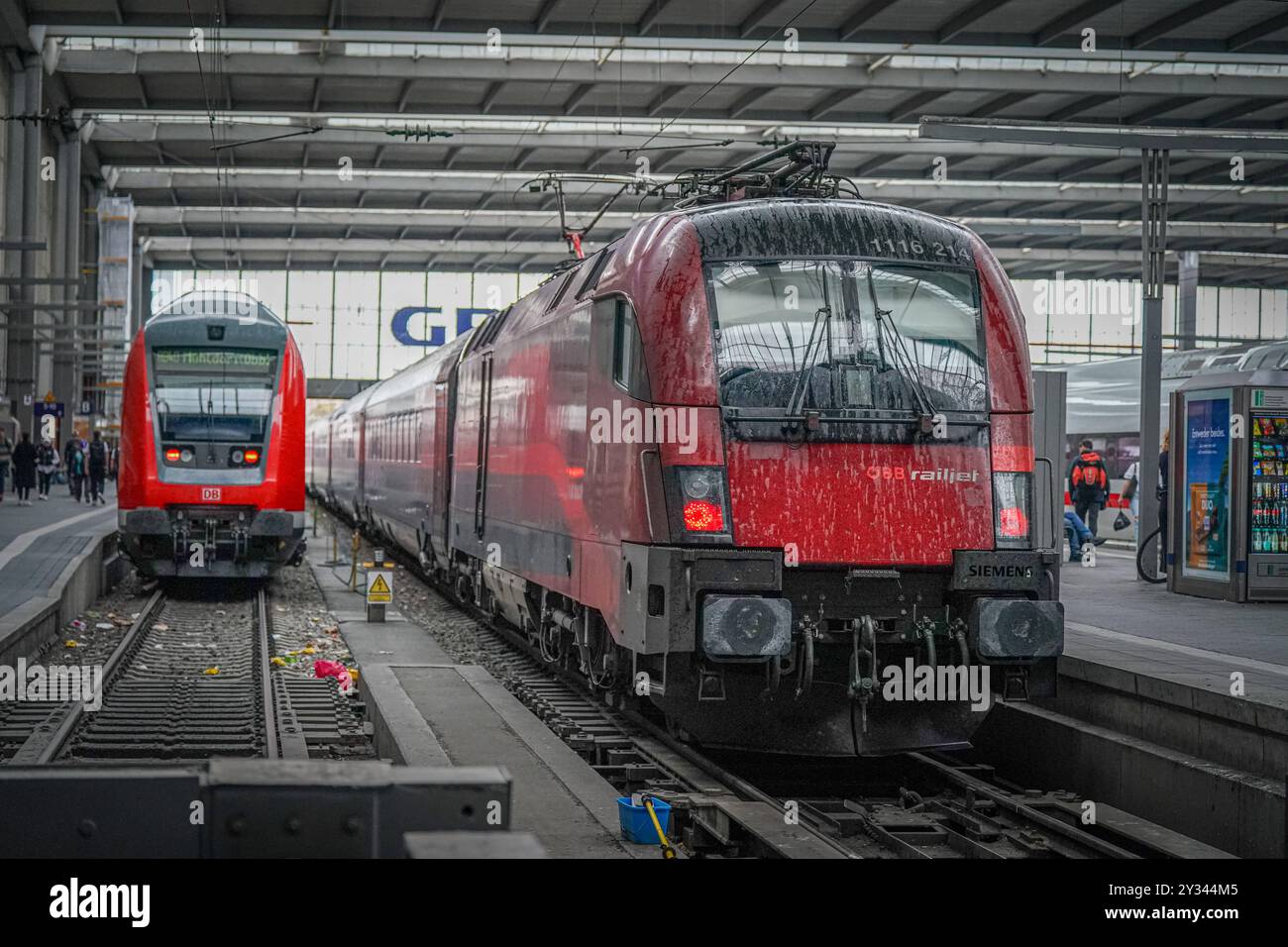 ÖBB Railjet, Siemens-Lok, Bahnsteig, Gleise, Bahnhofshalle, München Hauptbahnhof, Fernverkehr, Zugverkehr, Zugreinigung, Pendler, Zugfahrt, Lokomotive, Schieneninfrastruktur, Zugwartung, Bahnverkehr, Europäische Zugverbindungen, Reisen mit der Bahn, Zugverspätungen, Deutsche Bahn, Österreichische Bundesbahnen, Bahnmodernisierung, Umbauarbeiten, Pünktlichkeit im Zugverkehr, Herausforderungen im Bahnverkehr, Lokführerstreik, Wartungsarbeiten, Reiseverkehr, Schienenverkehr, Bahnkundenservice. *** ÖBB Railjet, locomotive Siemens, plate-forme, voies, hall de gare, gare centrale de Munich, long-di Banque D'Images