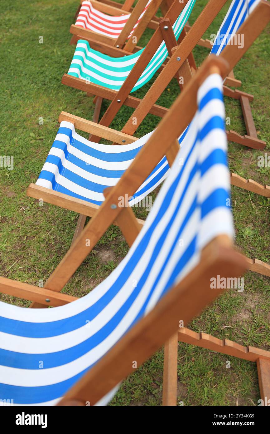 Transats sur herbe transats colorés rayés bleu blanc rouge vert rayures rayées Banque D'Images