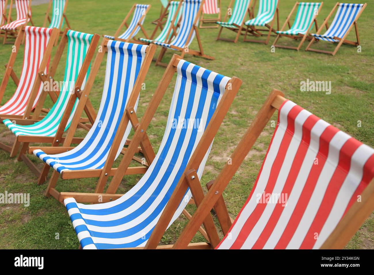 Transats sur herbe transats colorés rayés bleu blanc rouge vert rayures rayées Banque D'Images