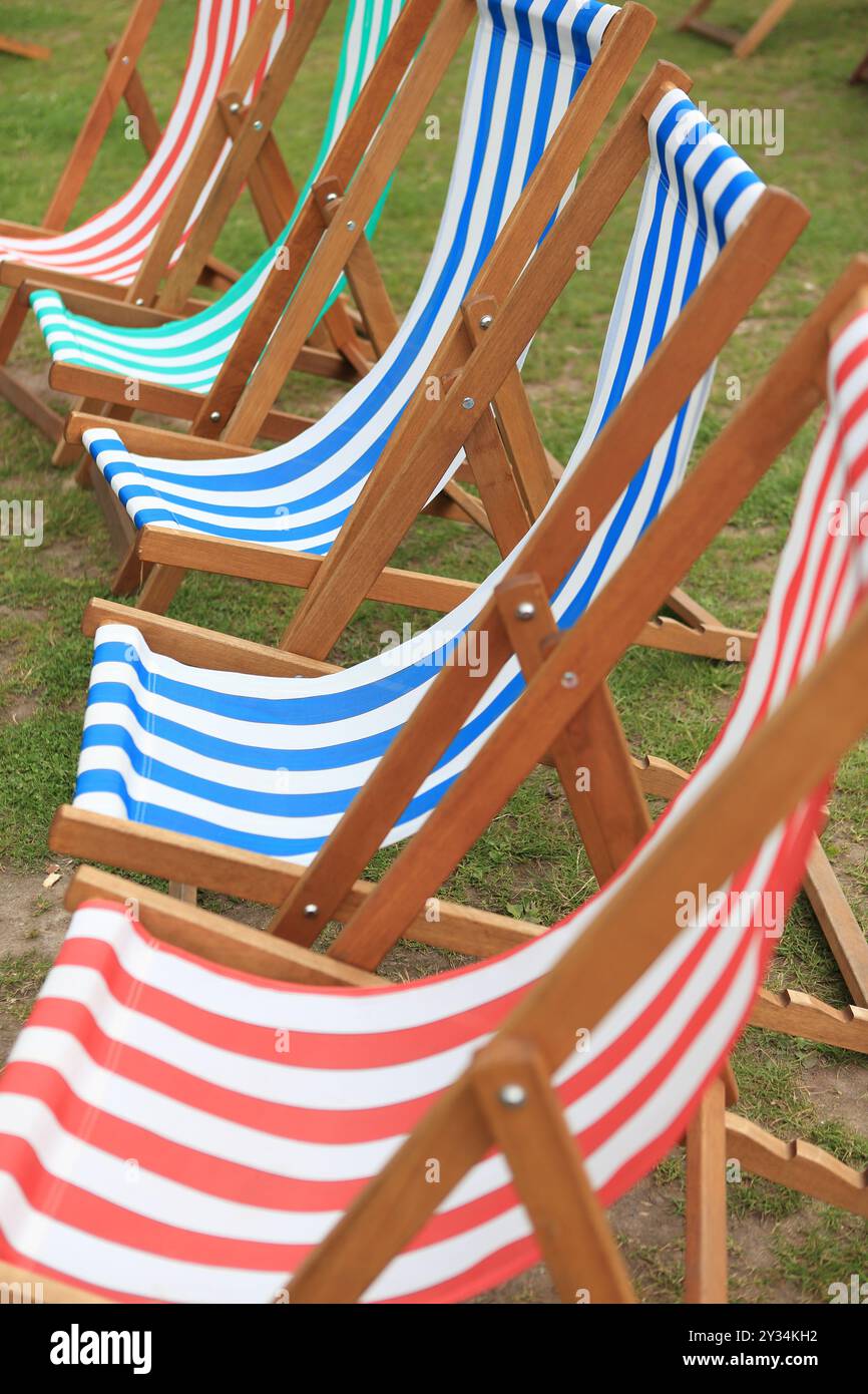 Transats sur herbe transats colorés rayés bleu blanc rouge vert rayures rayées Banque D'Images