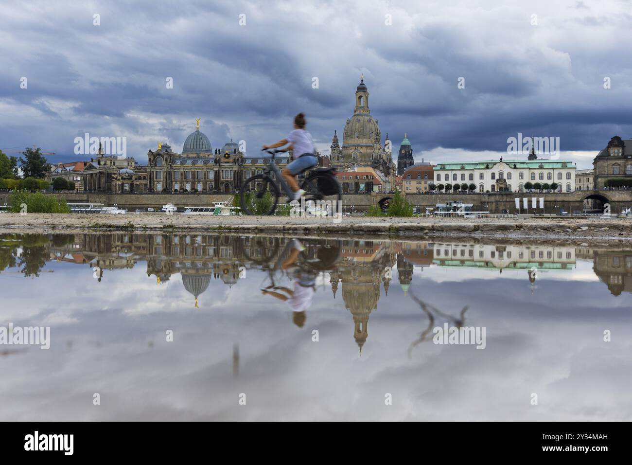 La silhouette de Dresde avec un cycliste et des nuages sombres derrière l'église notre-Dame se reflète dans une flaque sur la piste cyclable de l'Elbe, piste cyclable de l'Elbe, Banque D'Images