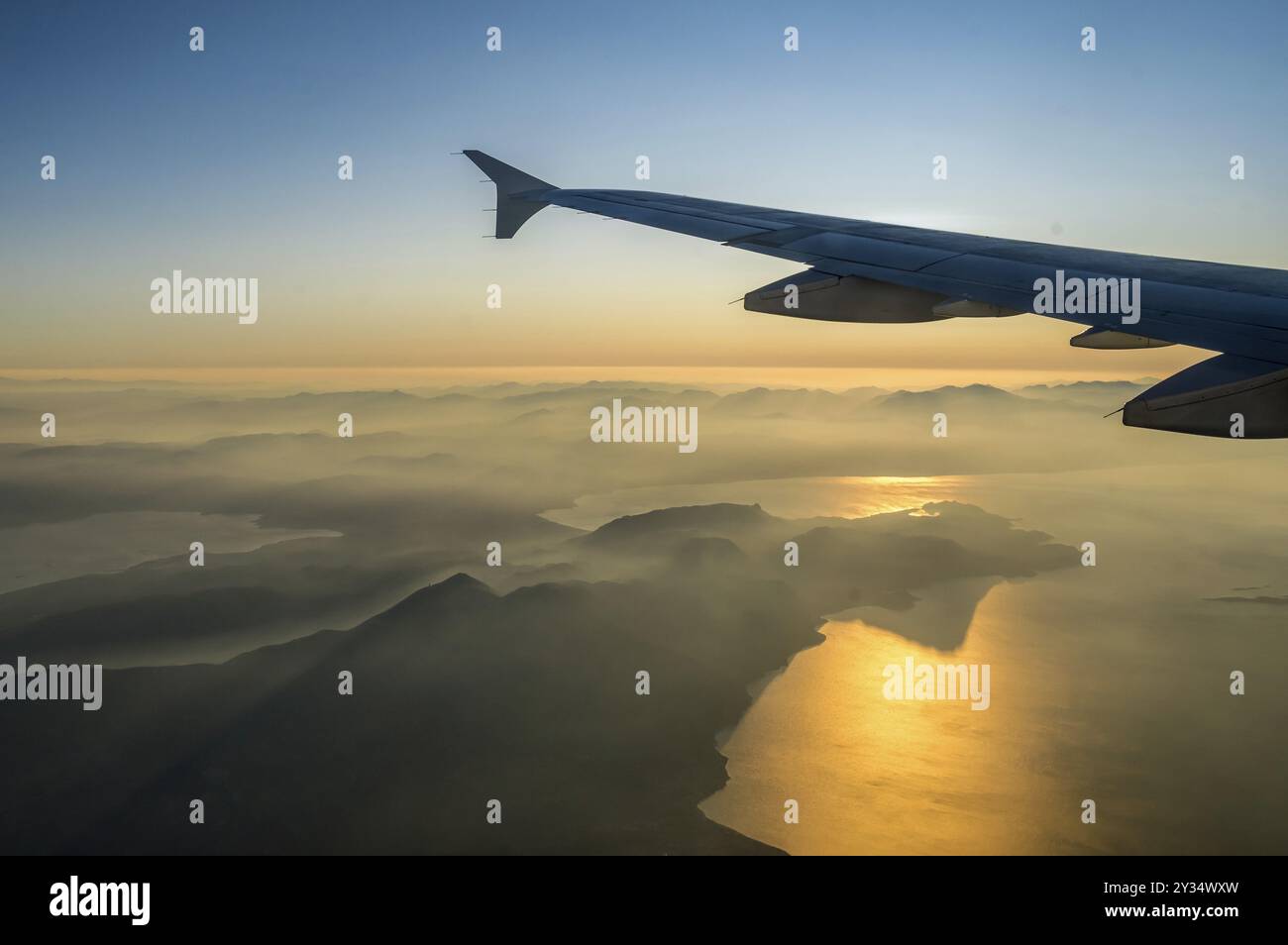 Voir l'avion de passagers sur aile gauche. Soleil brille comme un rayon de lumière sur l'aile. D'épais nuages ci-dessous sont éclairés par l'avion. Golden sun. Horizo Banque D'Images