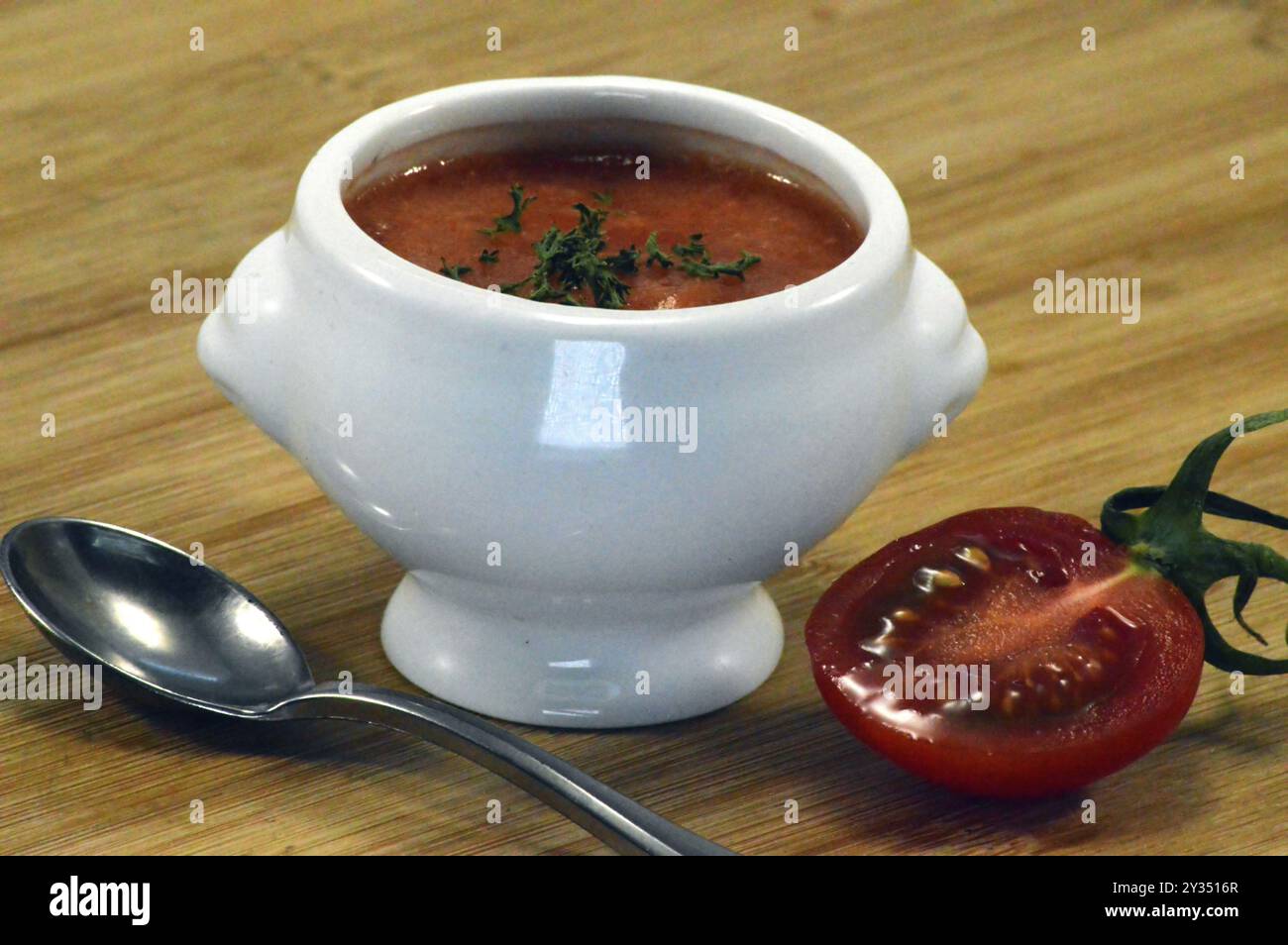 Crème de soupe de tomates dans un bol blanc avec une cuillère et une tomate cerise Banque D'Images