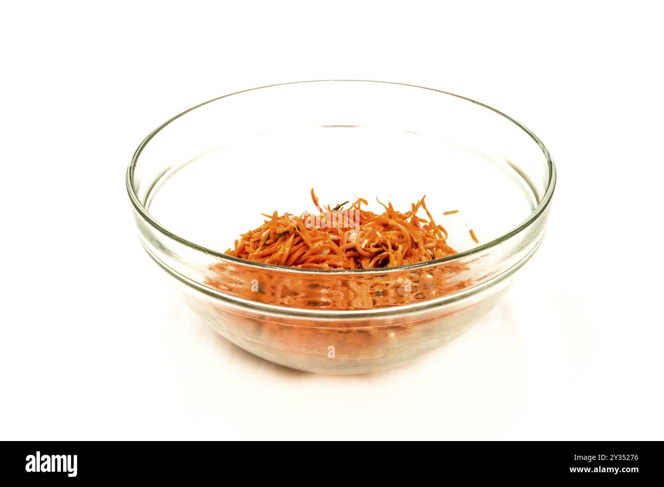 Salade de carottes râpée dans un bol transparent sur fond blanc Banque D'Images
