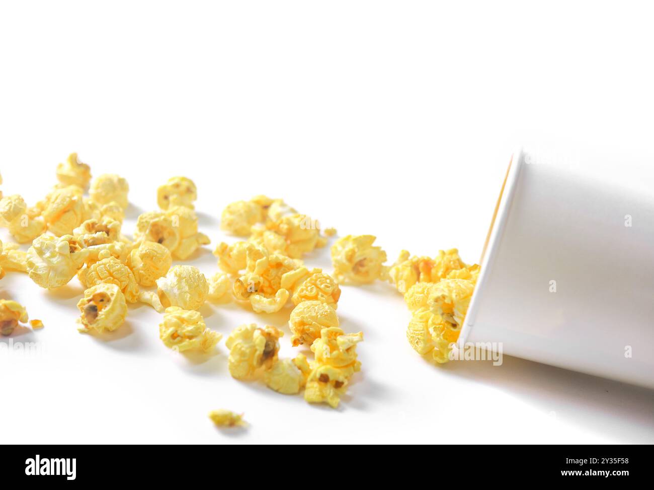 Image isolée de pop-corn dans une tasse en papier sur fond blanc, mettant en valeur les grains moelleux et dorés débordant sur les bords, parfait pour eux Banque D'Images