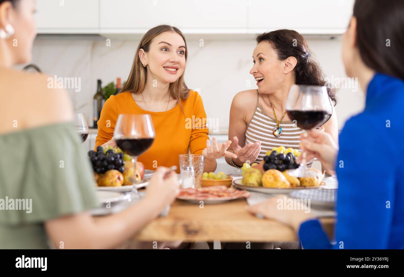 Des femmes heureuses se sont rassemblées autour d'une table festive ; participant à des discussions animées et appréciant les délices du vin Banque D'Images