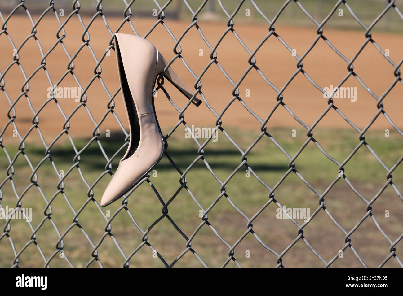 chaussures beiges à talons hauts suspendues à la clôture de maillons de chaîne de terrain de baseball Banque D'Images