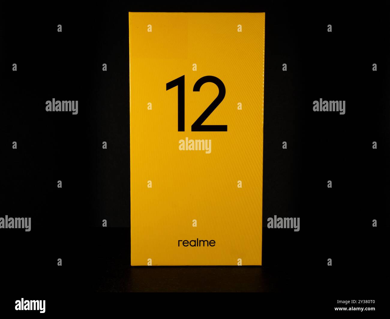 Gros plan d'une boîte jaune Realme 12 sur fond sombre. L'image met en valeur la technologie moderne et la marque. Banque D'Images