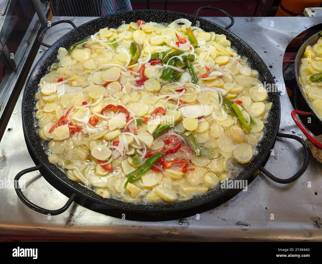 Pommes de terre avec légumes frits dans une grande casserole à l'extérieur lors d'une fiesta en Espagne Banque D'Images
