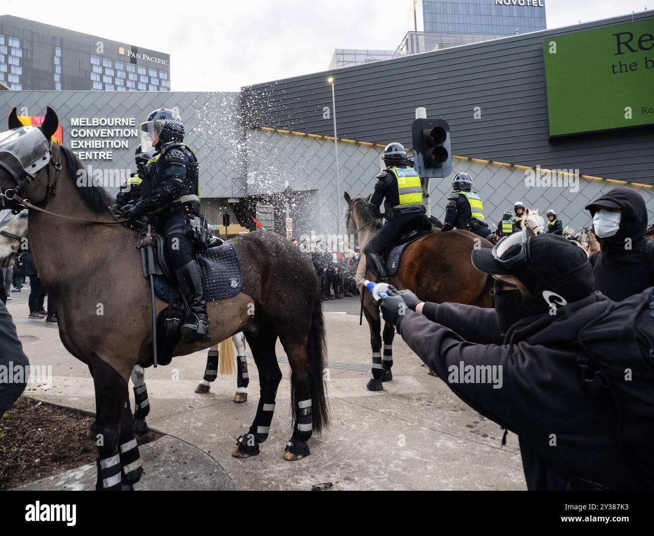 Melbourne, Australie. 11 septembre 2024. Un manifestant masqué pulvérise de l'eau sur un officier monté. Un blocus planifié et une manifestation contre les Forces terrestres 2024, la plus grande exposition de l'industrie de la défense dans l'hémisphère sud, ont éclaté en affrontements avec la police tout au long de la journée. Les manifestants tentant d'empêcher l'entrée de la convention ont jeté des objets et des liquides sur les agents, construit de petits barrages et déclenché des incendies de poubelles, tandis que la police a utilisé la force, le gaz lacrymogène, des grenades paralysantes et des balles en caoutchouc sur les manifestants, cheval, eau (photo Alex Zucco/SOPA images/Sipa USA) crédit : Sipa USA/Alamy Live News Banque D'Images