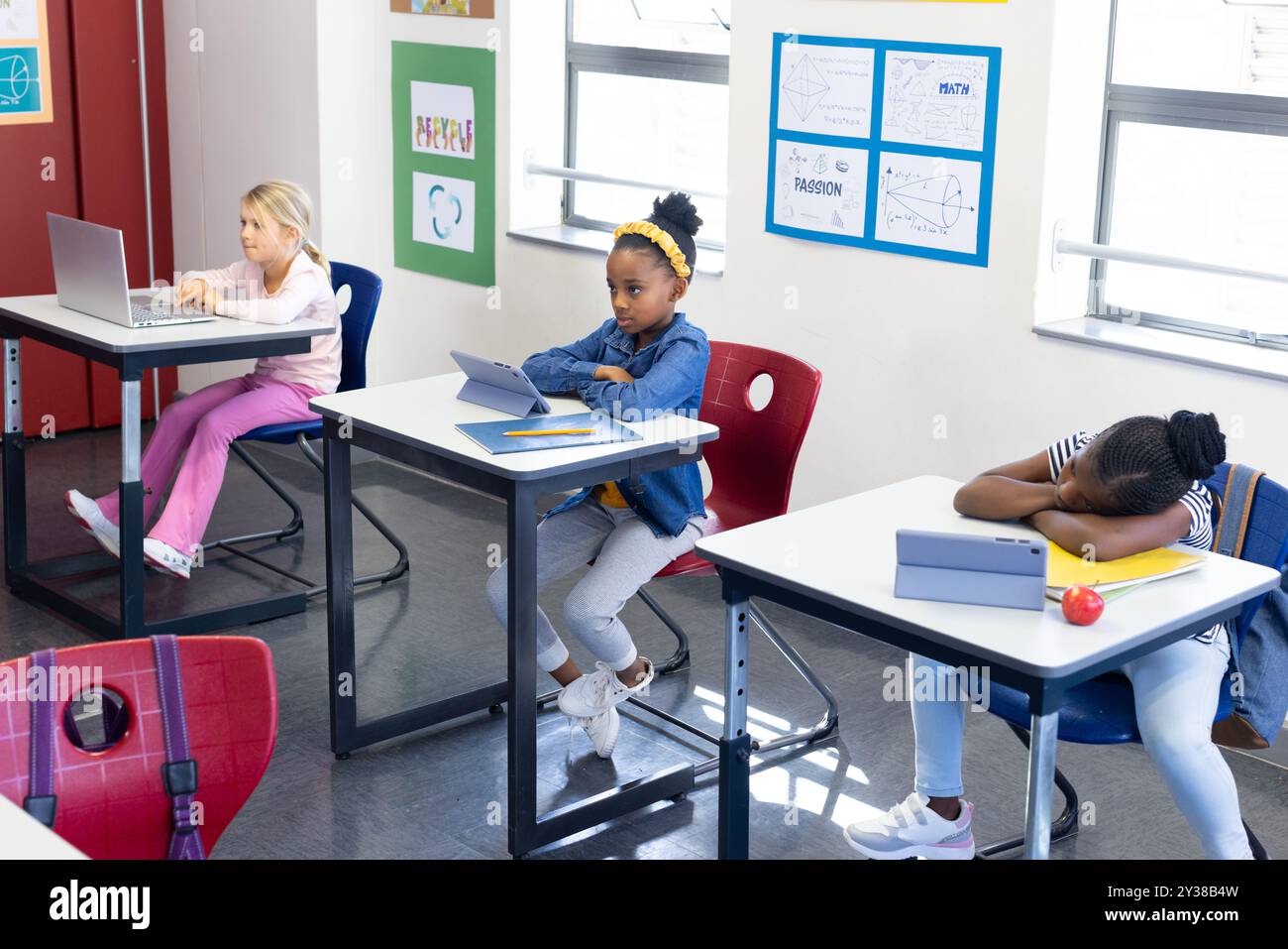 À l'école, les filles multiraciales utilisant des tablettes et un ordinateur portable en classe, étudiant attentivement Banque D'Images