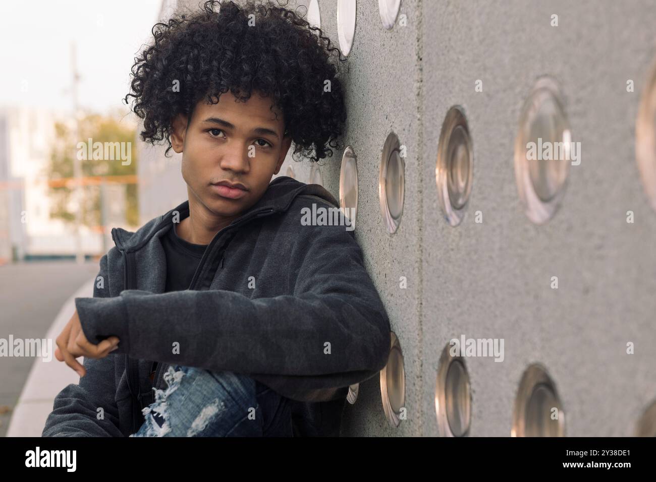 adolescent sérieux avec les cheveux bouclés regardant la caméra Banque D'Images